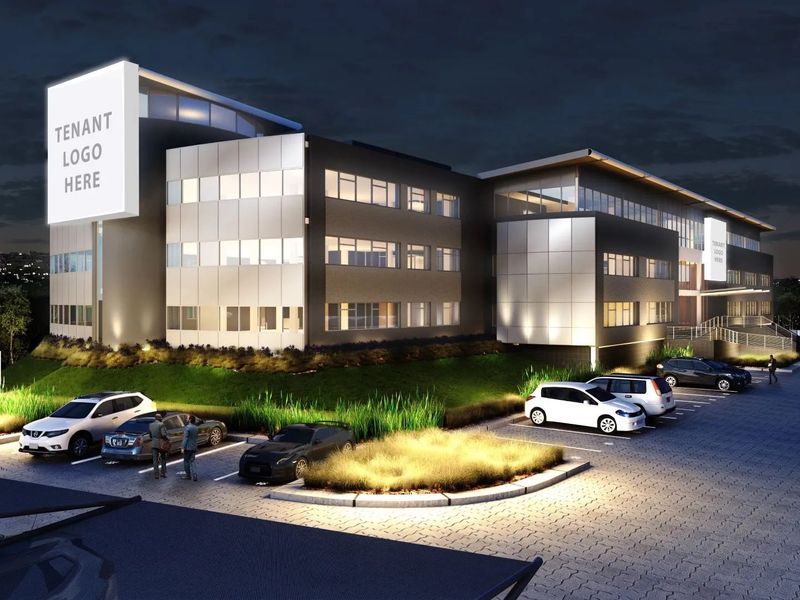 A modern multi-story commercial office building at night, featuring a paved parking area, professional exterior lighting, and prominent signage opportunities.
