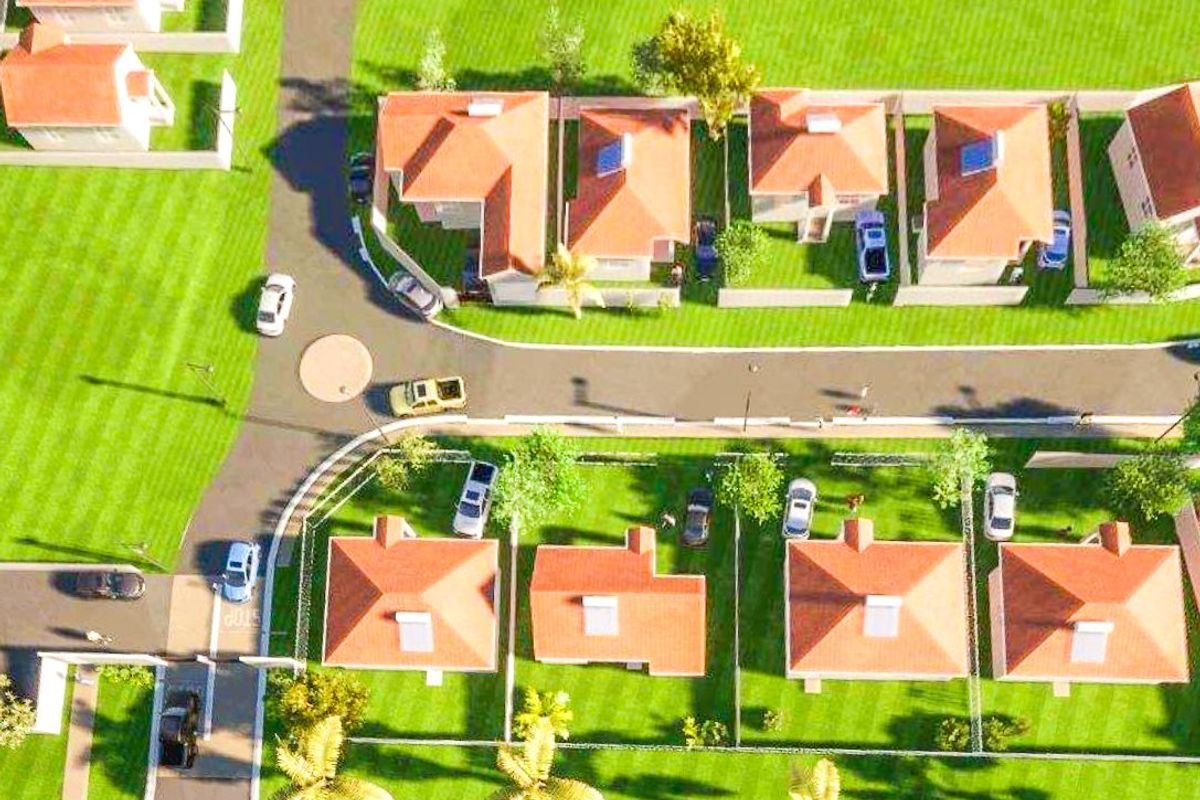 An aerial view of a residential estate featuring multiple detached houses with tiled roofs, private gardens, and paved street access.
