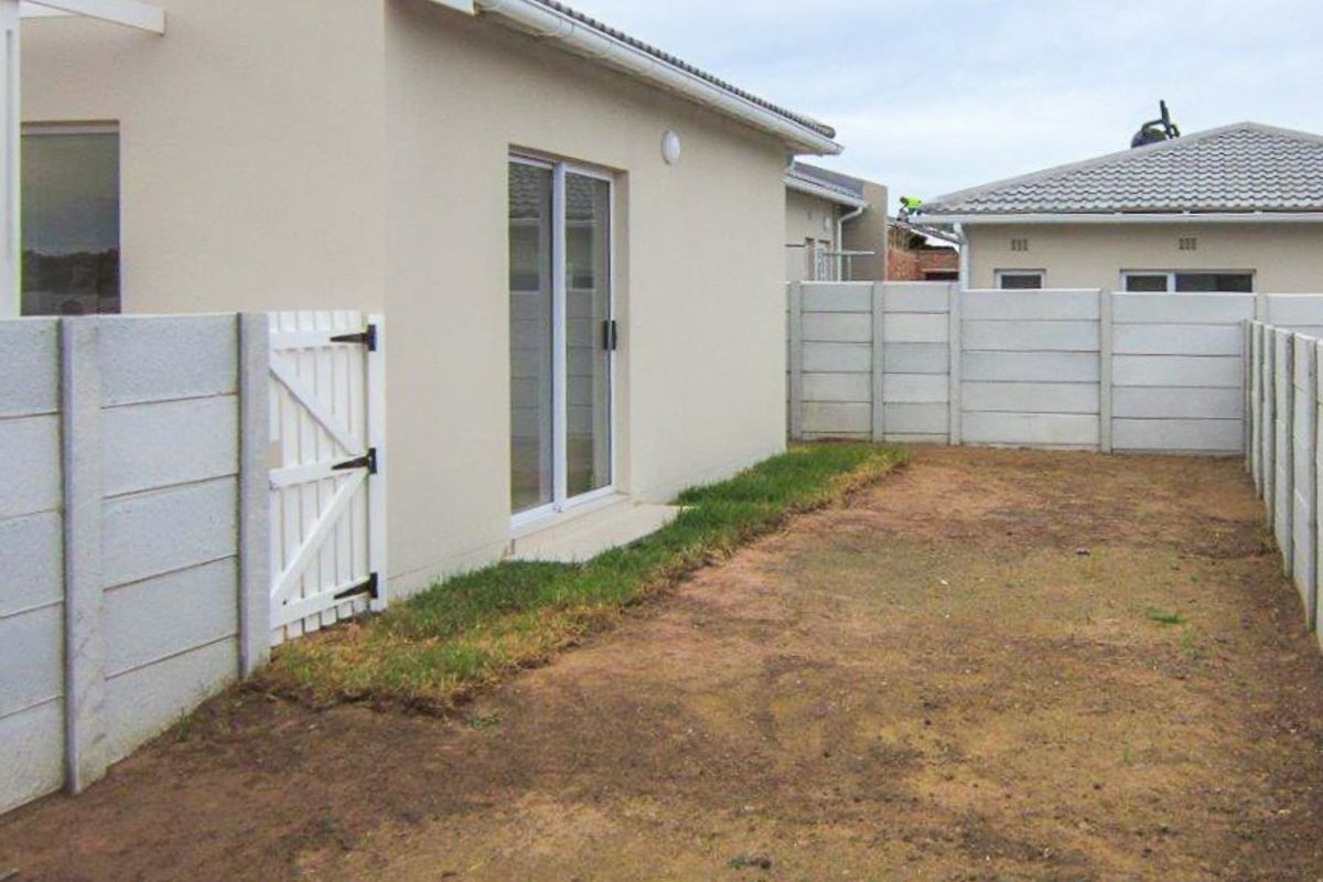 Rear exterior view of the property featuring a sliding door access and a fully enclosed yard with precast concrete boundary walls.