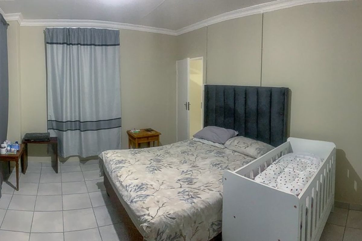 A functional bedroom featuring tiled flooring, built-in cupboard space, and neutral wall finishes.