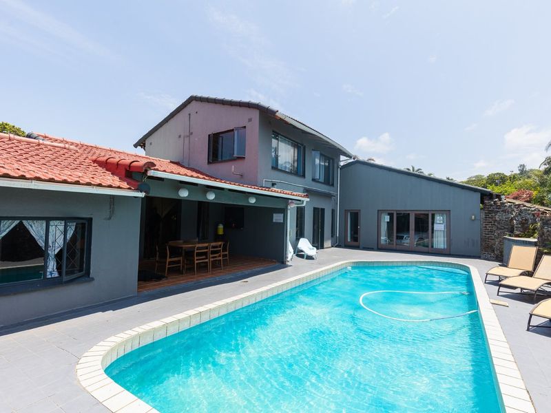 A spacious outdoor pool area featuring a swimming pool, a covered patio space, and direct access to the home through sliding glass doors.