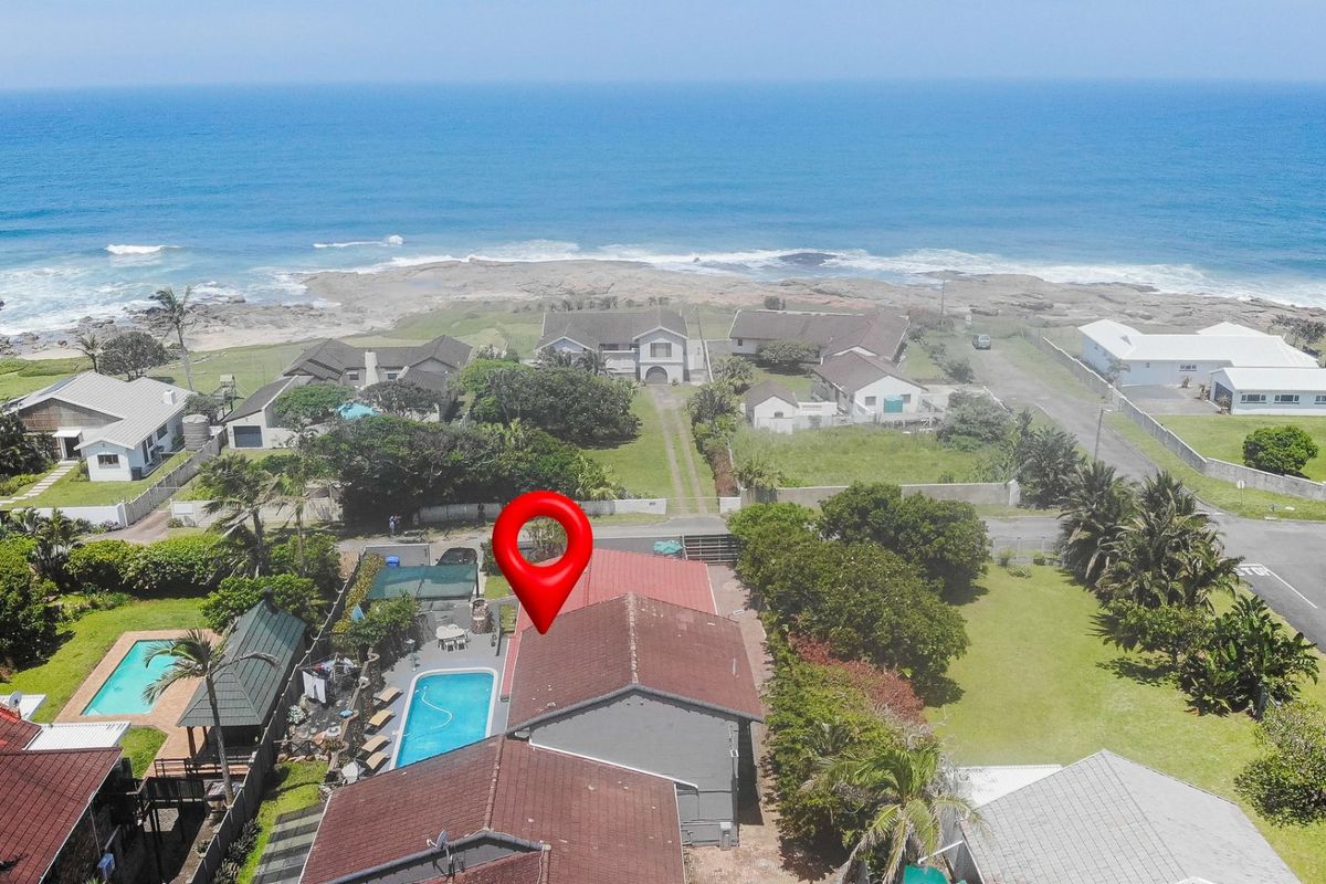 Aerial view of a coastal property featuring a swimming pool, tiled roof, and proximity to the ocean.