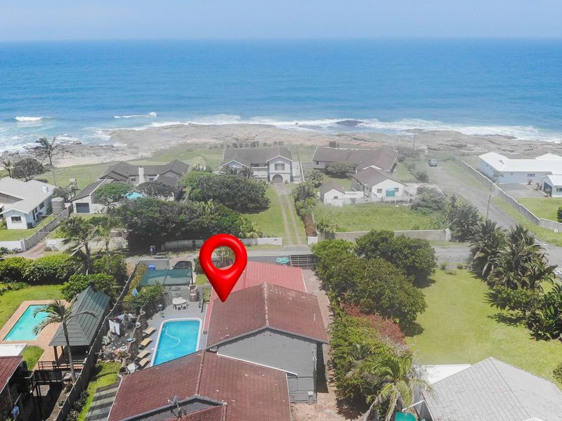 Aerial view of a coastal property featuring a swimming pool, tiled roof, and proximity to the ocean.
