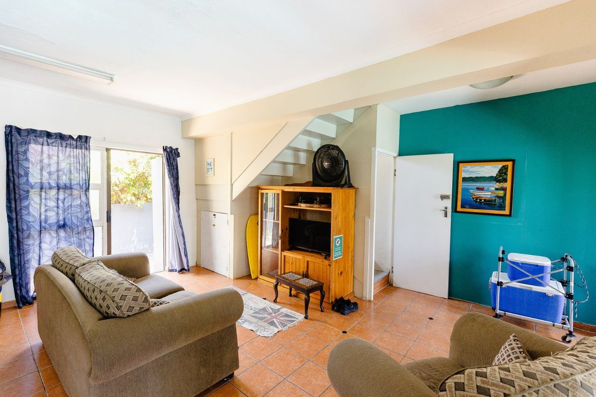A living room featuring tiled flooring, a staircase, and a sliding glass door providing access to the exterior.
