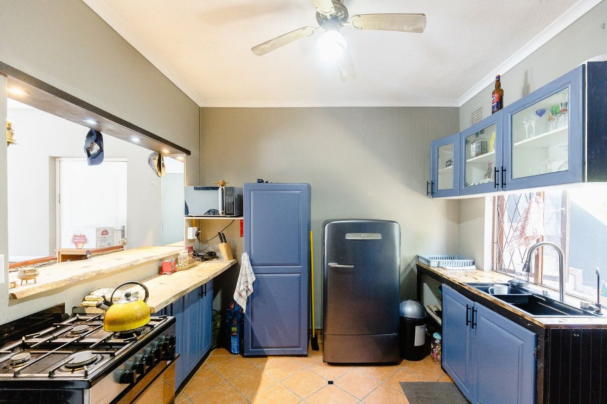 Functional kitchen featuring blue cabinetry, timber countertops, a gas stove, and a breakfast bar pass-through to the adjacent living area.