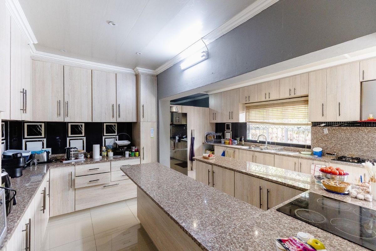 Spacious kitchen featuring extensive granite countertops, ample built-in cabinetry, a central island, and a functional layout with a separate scullery area.
