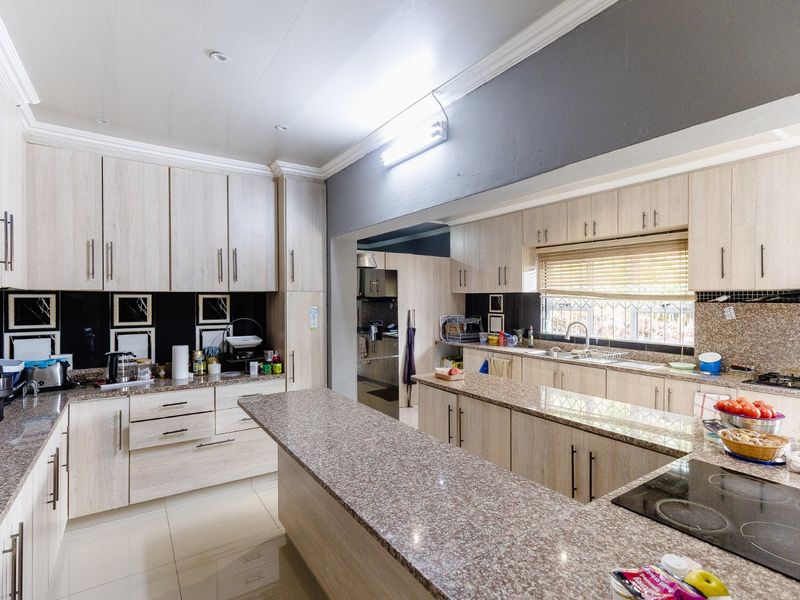 Spacious kitchen featuring extensive granite countertops, ample built-in cabinetry, a central island, and a functional layout with a separate scullery area.