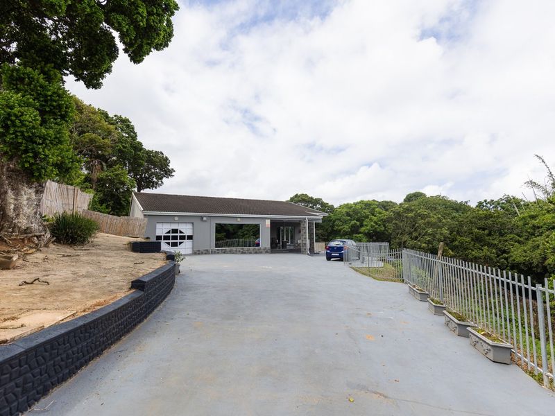Front exterior view of the property featuring a spacious concrete driveway, secure metal fencing, and a single garage entrance.