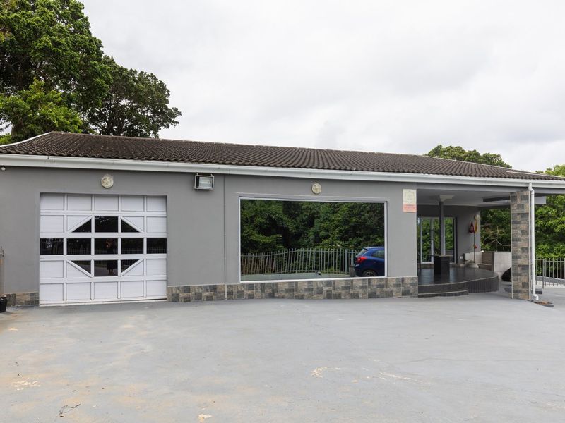 Front exterior view of the property featuring a garage, covered entrance, and paved driveway with stone cladding accents.