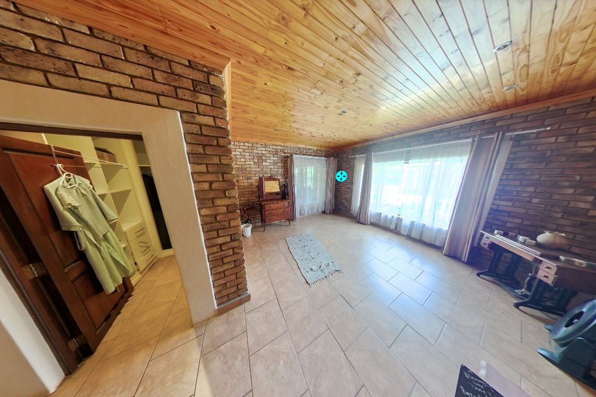 Spacious bedroom featuring exposed brick walls, timber ceiling, tiled flooring, and an integrated walk-in closet area.