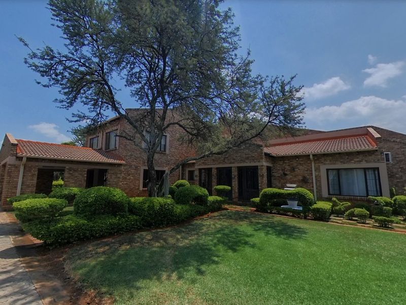 A well-maintained face brick family home featuring a spacious paved driveway, established landscaped garden, and classic tiled roof architecture.