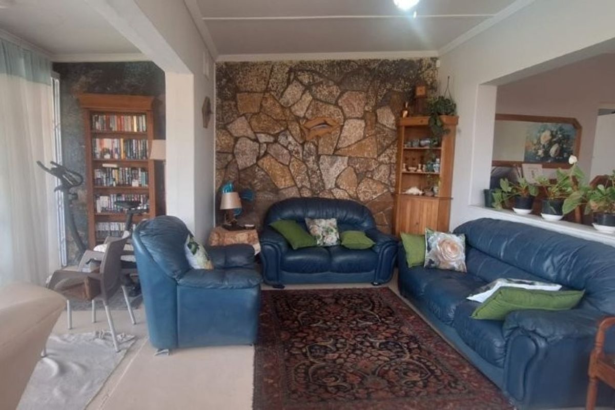 A spacious living room featuring a prominent stone accent wall, large sliding glass doors, and an open-plan layout connecting to adjacent living areas.