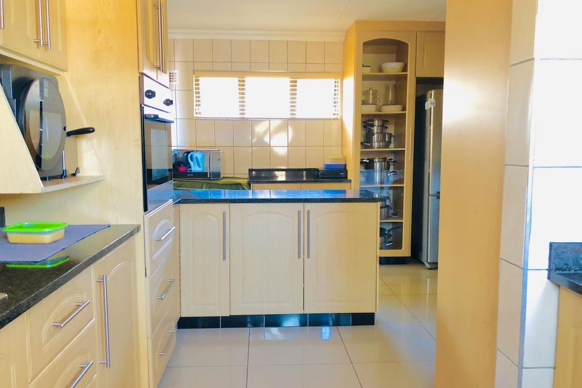 A functional kitchen featuring light wood cabinetry, dark granite countertops, tiled backsplash, and built-in oven with ample storage space.
