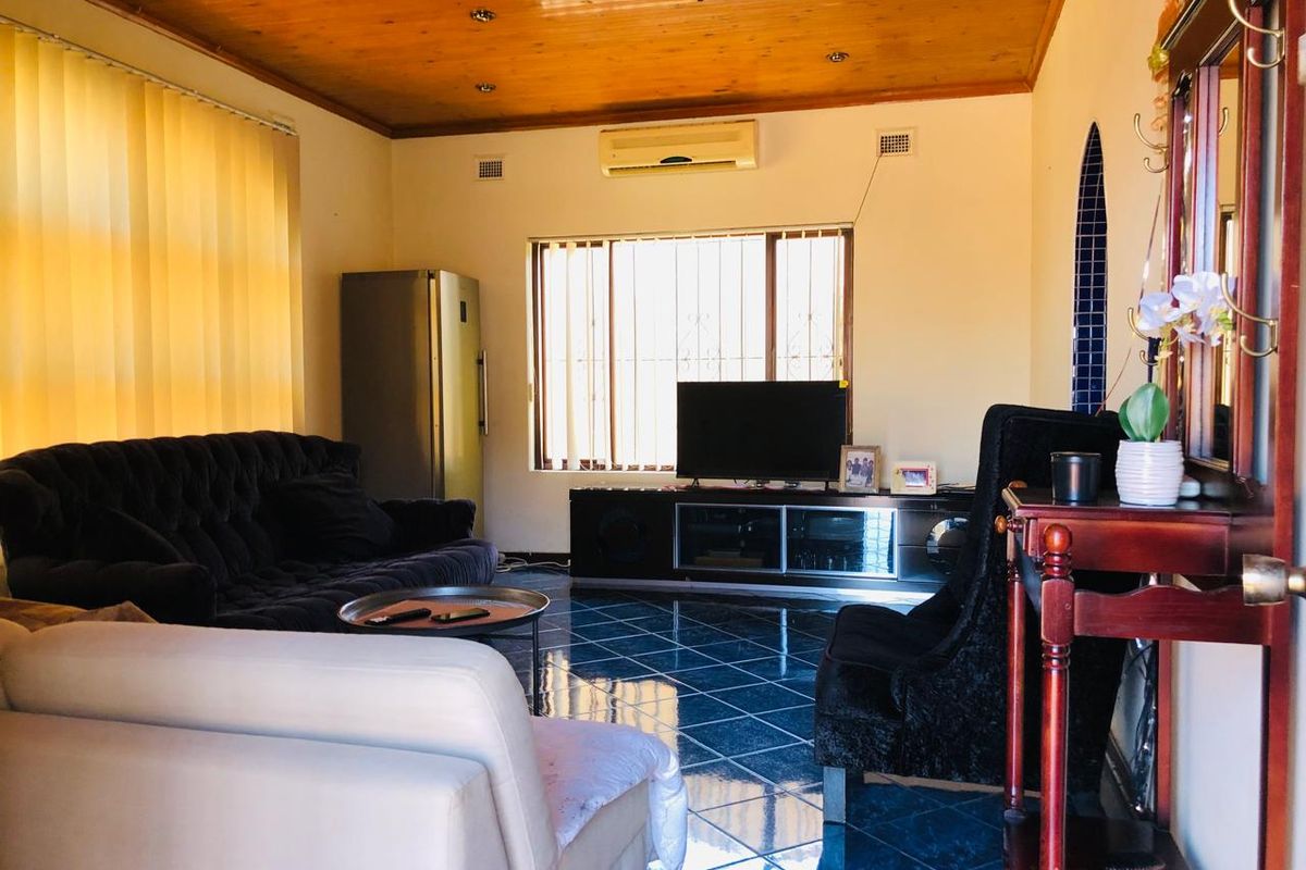 A living room featuring timber ceiling paneling, tiled flooring, and a wall-mounted split system air conditioner.