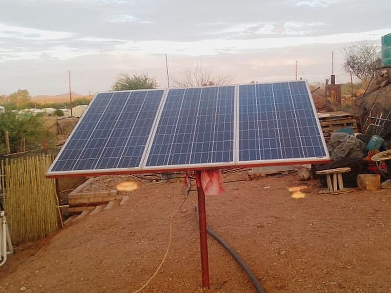 A ground-mounted solar panel array installed in an outdoor garden area.