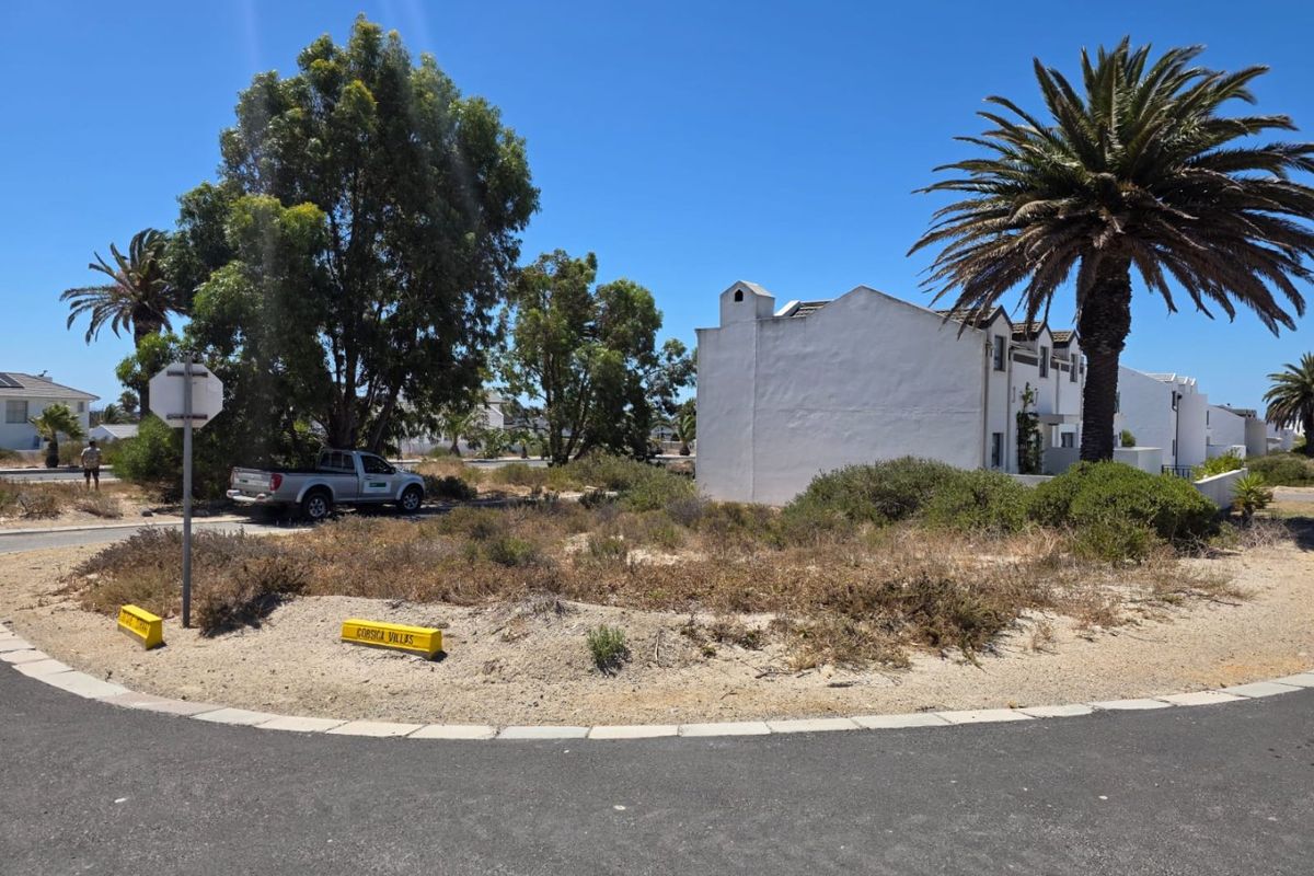 A street-level view of the property entrance and surrounding neighbourhood landscape, featuring paved road access and established vegetation.