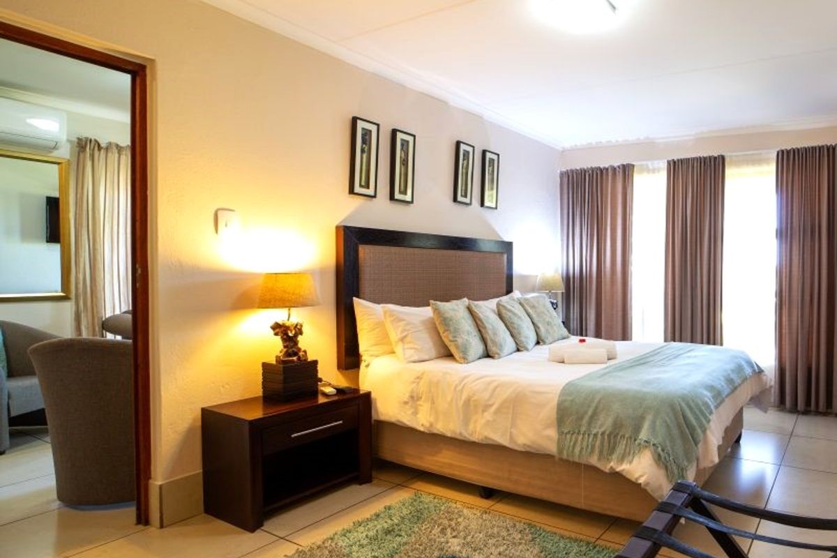 A well-maintained bedroom featuring tiled flooring, neutral wall finishes, and a doorway leading to an adjacent living space.