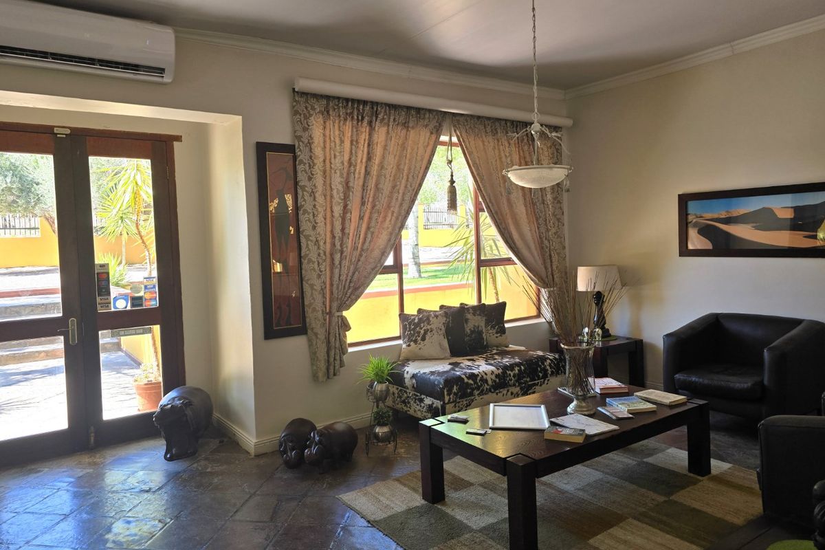 A comfortable living area featuring tiled flooring, a split-system air conditioner, and large windows providing natural light and access to the exterior.