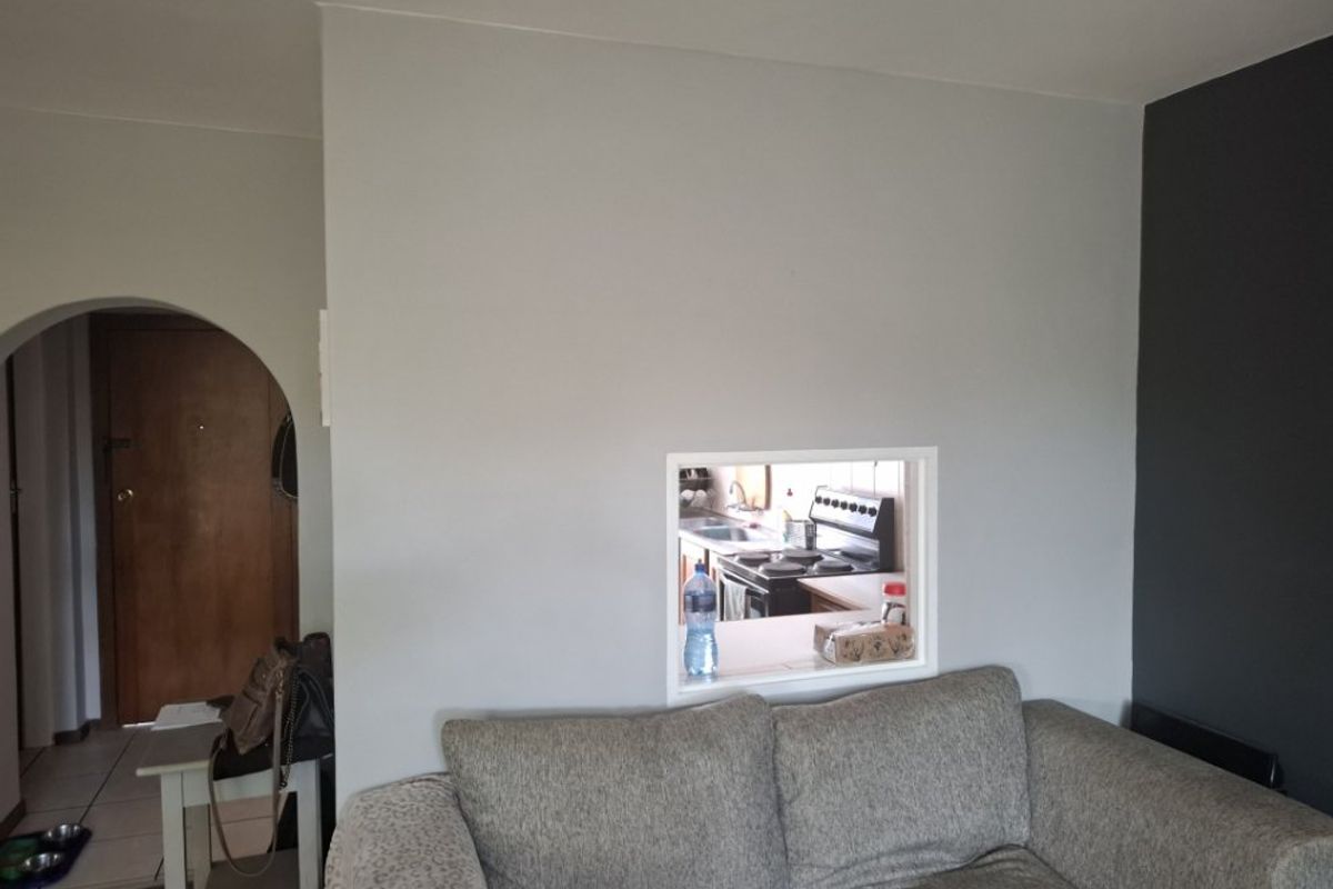 Living room featuring an arched entryway and a serving hatch providing a view into the kitchen area.