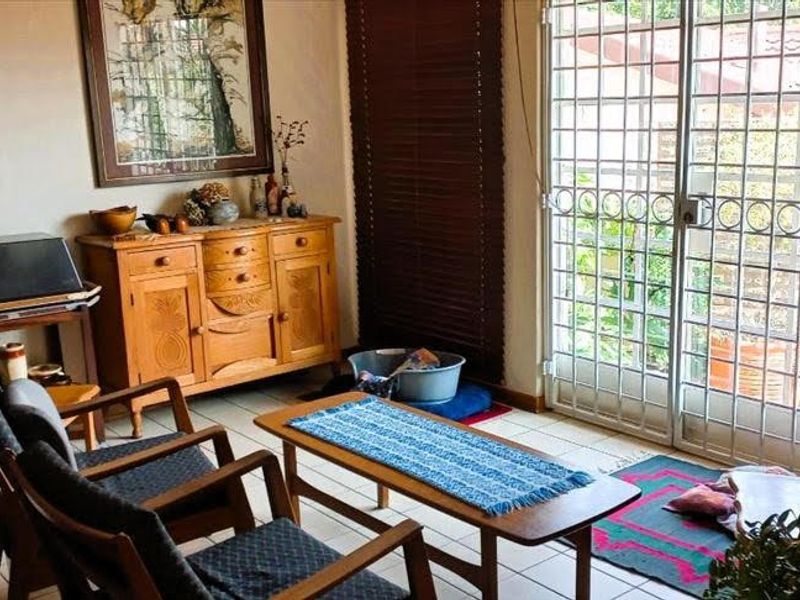 A living area featuring tiled flooring, venetian blinds, and a sliding glass door with a security gate leading to the exterior.