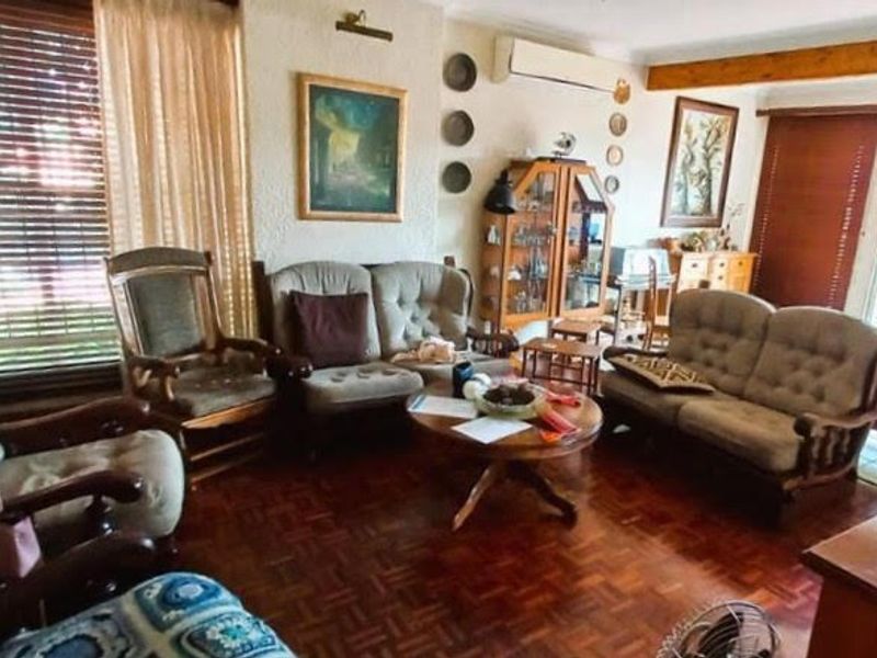 A traditional living room featuring parquet flooring, an exposed timber ceiling beam, and a wall-mounted split-system air conditioner.