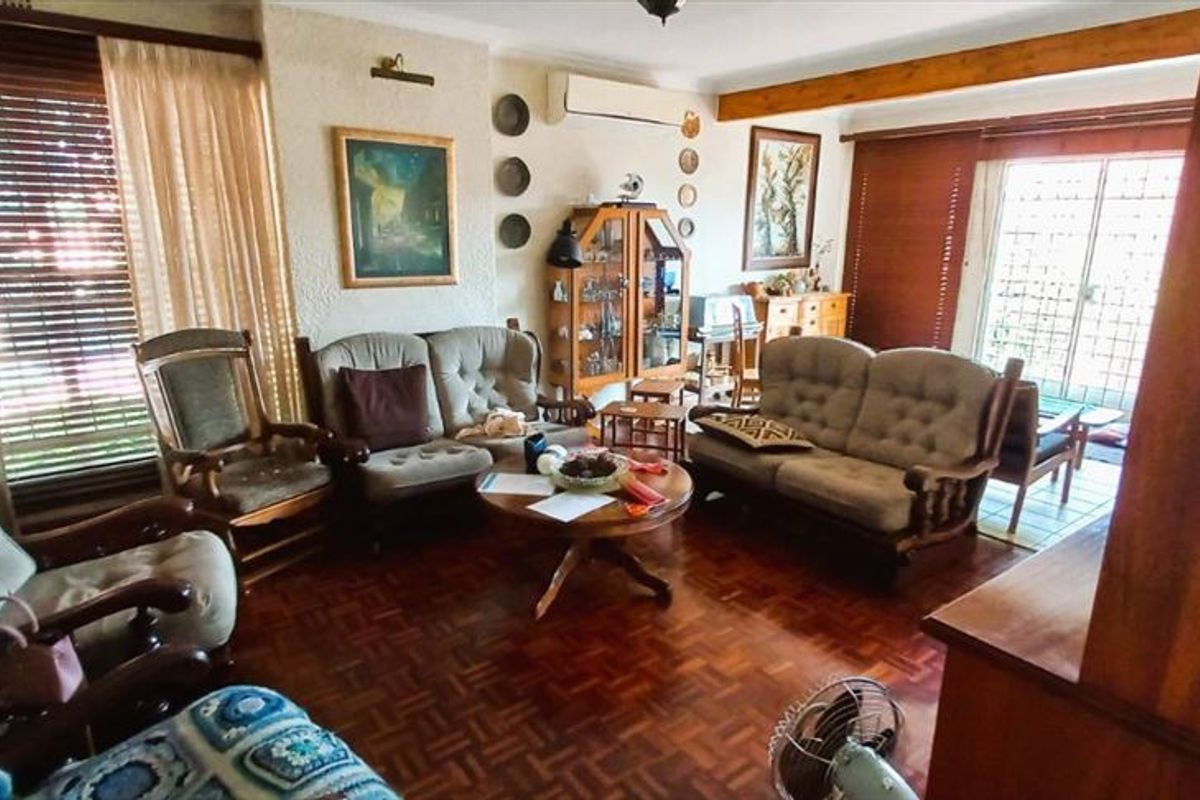 Spacious living room featuring classic parquet flooring, an exposed timber ceiling beam, and a split-system air conditioner, with direct access to the outdoor area.