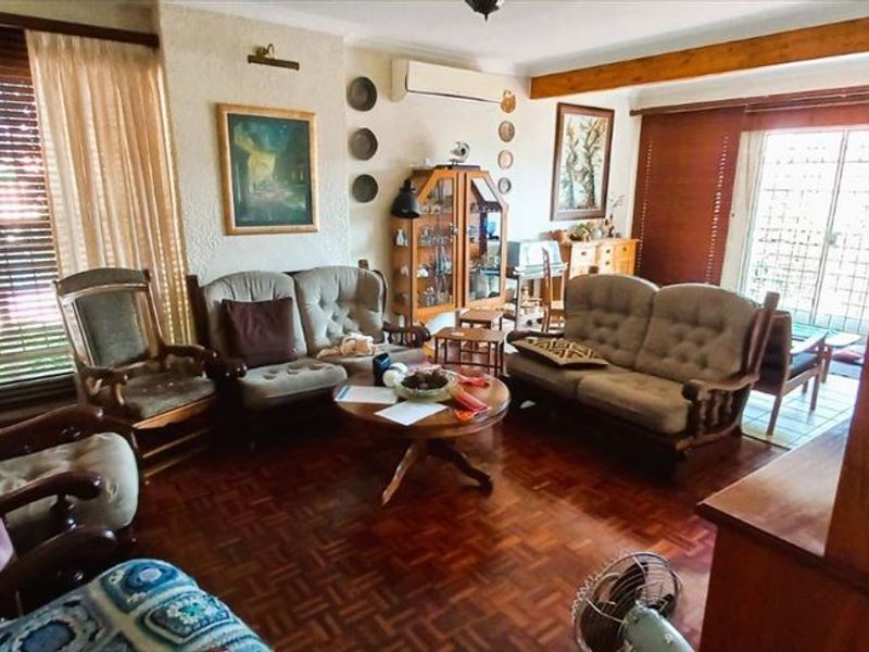 Spacious living room featuring classic parquet flooring, an exposed timber ceiling beam, and a split-system air conditioner, with direct access to the outdoor area.