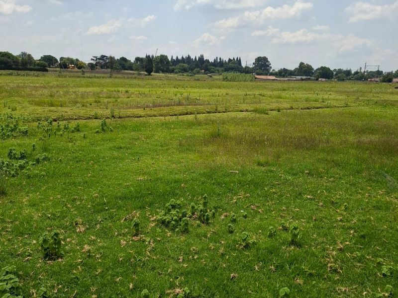 A wide, open expanse of vacant residential land featuring natural grass coverage and a clear view of the surrounding landscape.