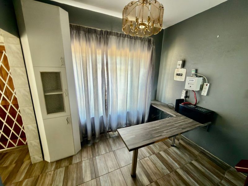 A functional home office space featuring tiled flooring, built-in cabinetry, and a wall-mounted desk setup with integrated electrical points.