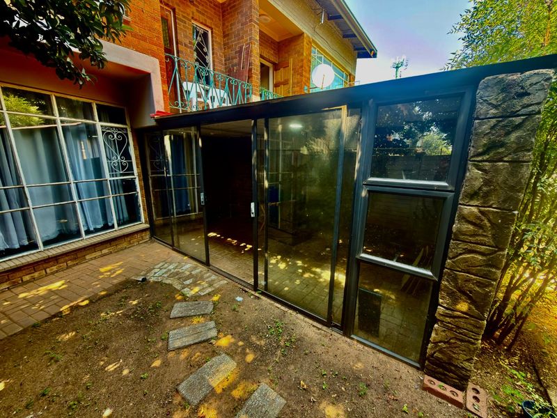 Rear exterior view of the apartment featuring a paved patio area, sliding glass doors, and a brick facade with a balcony above.