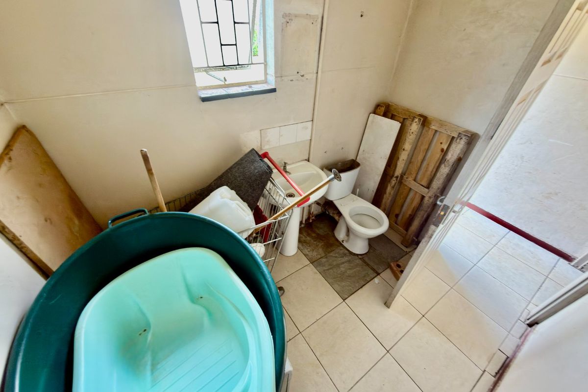 A small bathroom featuring a toilet and pedestal basin, requiring renovation and cosmetic updates to improve the overall condition and functionality of the space.