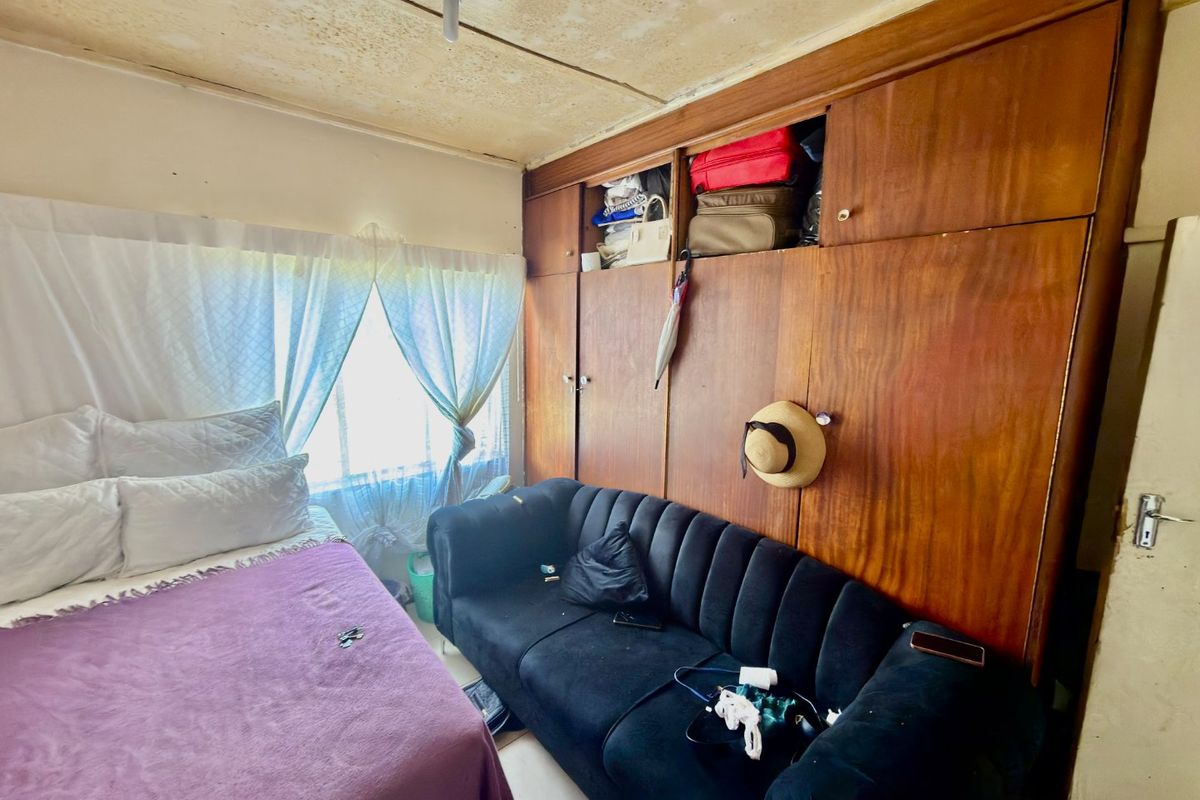 A bedroom featuring built-in wooden cabinetry. The room requires ceiling repairs and general refurbishment to improve its overall condition and appeal.