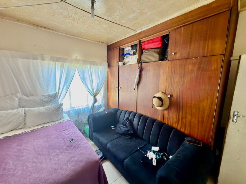 A bedroom featuring built-in wooden cabinetry. The room requires ceiling repairs and general refurbishment to improve its overall condition and appeal.