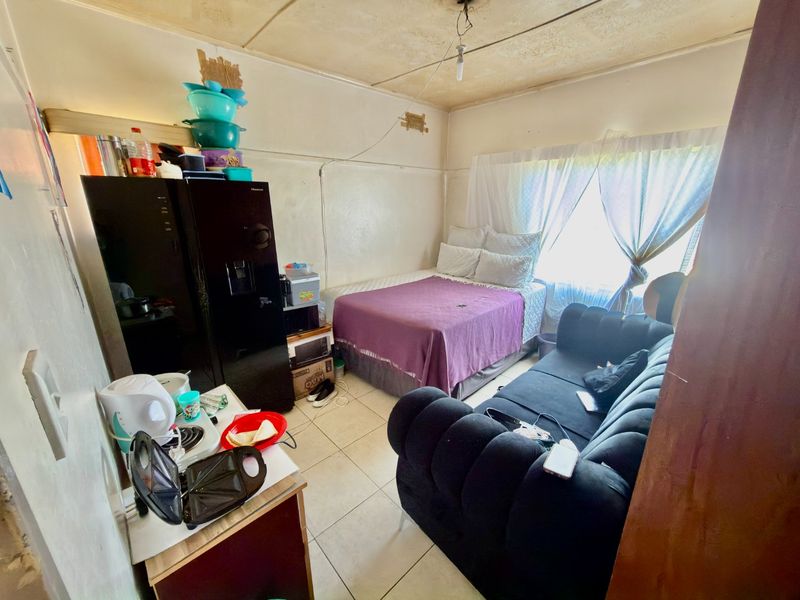 Compact open-plan living and sleeping area featuring tiled flooring and requiring ceiling maintenance and cosmetic updates.