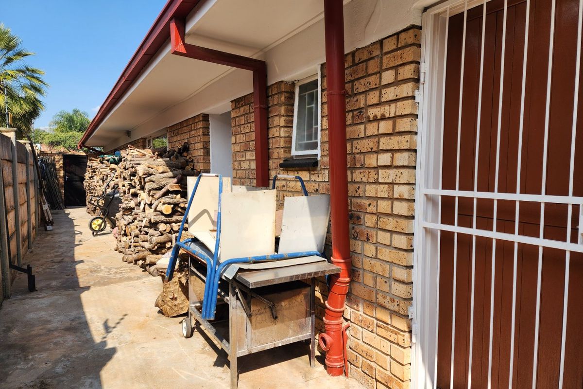 A side exterior walkway featuring face brick walls, a metal security gate, and integrated guttering systems along the roofline.