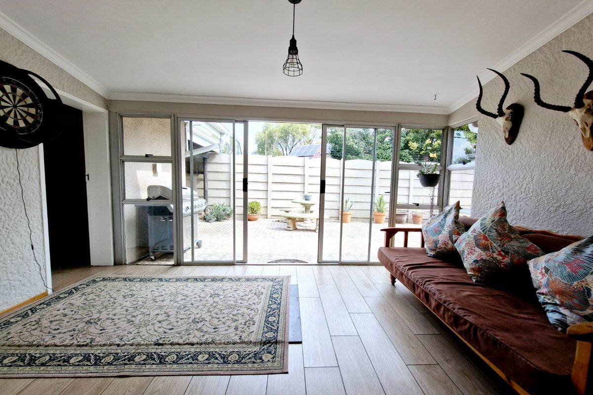 A bright living room featuring wood-look tiled flooring and large sliding glass doors that provide seamless access to the rear patio area.