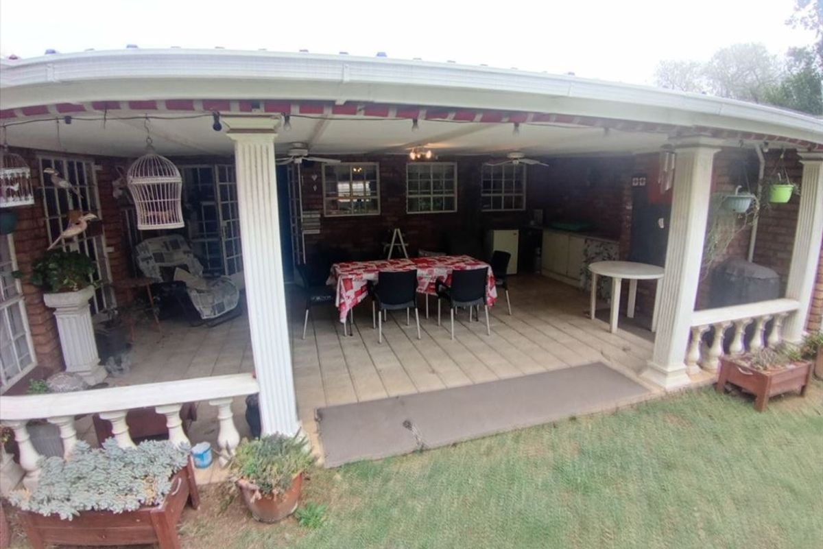 A covered outdoor patio area featuring brick columns, a balustrade, and ceiling fans, providing a functional space for outdoor dining and relaxation.