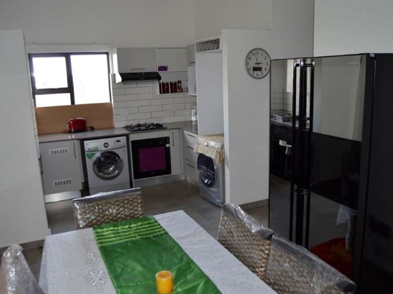 A functional kitchen featuring built-in cabinetry, a gas hob, an integrated oven, and a subway tile backsplash, with tiled flooring throughout.