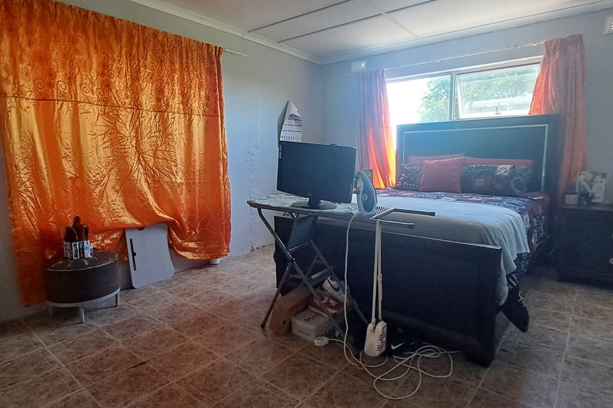 A bedroom featuring tiled flooring and sliding windows, requiring cosmetic updates to improve the overall aesthetic and finish.