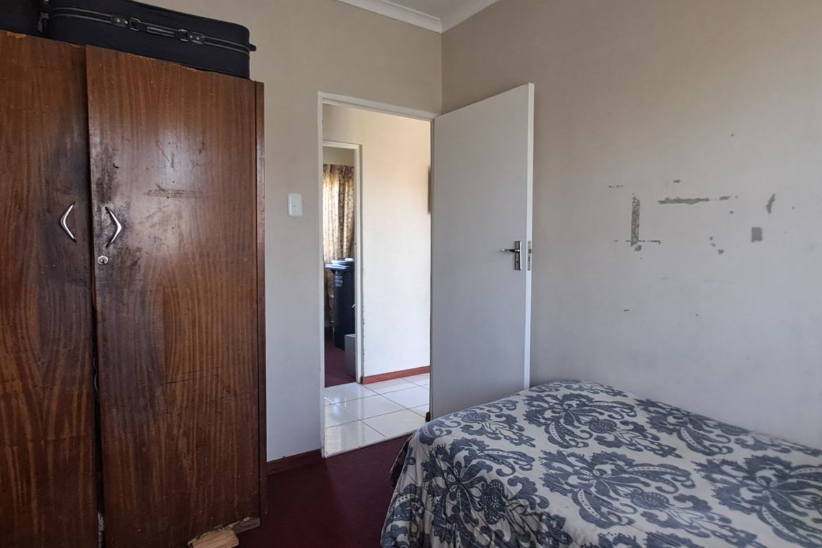 A bedroom featuring neutral walls and carpeted flooring, requiring minor cosmetic updates to the wall finishes.