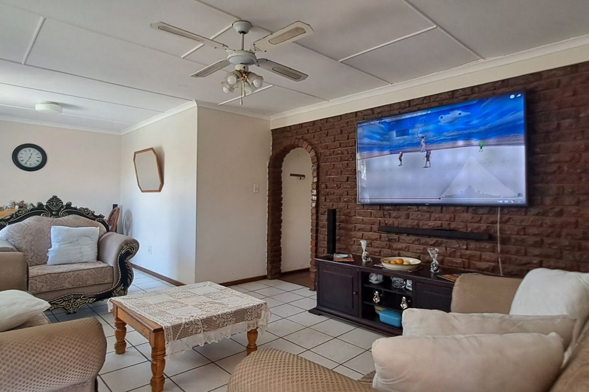 Living room featuring an exposed brick accent wall, tiled flooring, and an arched doorway leading to adjacent spaces.