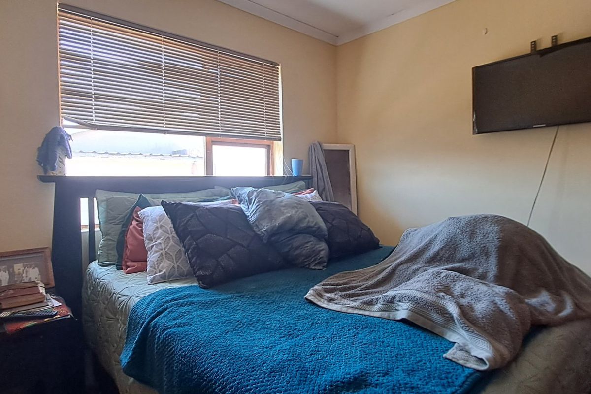 A standard bedroom featuring a wall-mounted television and window with venetian blinds.
