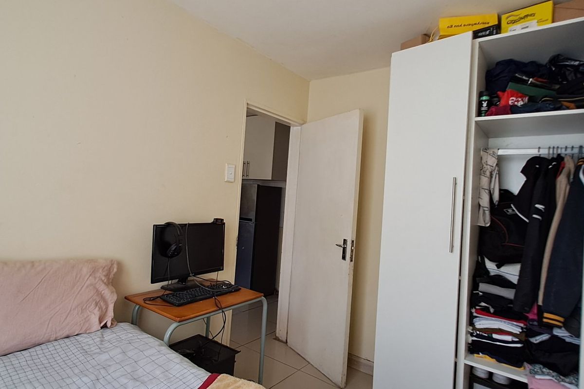 A functional bedroom featuring tiled flooring and a built-in wardrobe, providing practical storage space within the apartment.