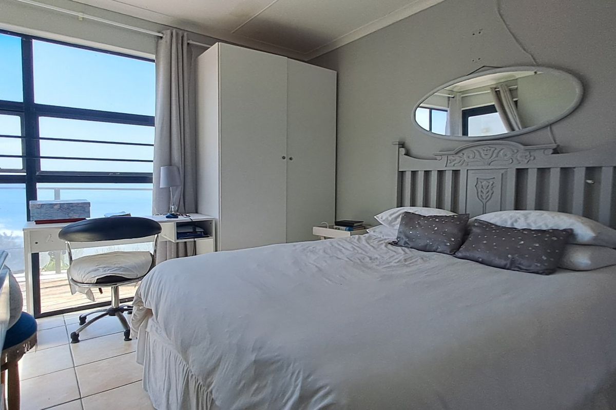 A bedroom featuring tiled flooring, a built-in wardrobe, and a large window providing natural light and an exterior view.