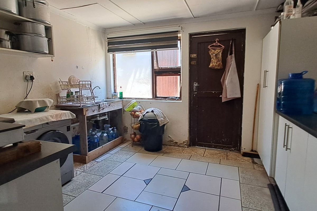 A functional kitchen space featuring tiled flooring, built-in cabinetry, and direct access to the exterior, offering potential for modernization and cosmetic updates.