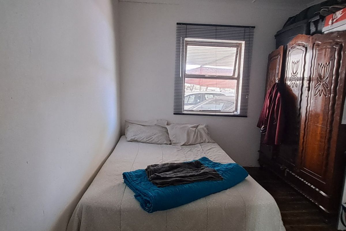 A functional bedroom featuring a window with venetian blinds, providing natural light and a view of the exterior.
