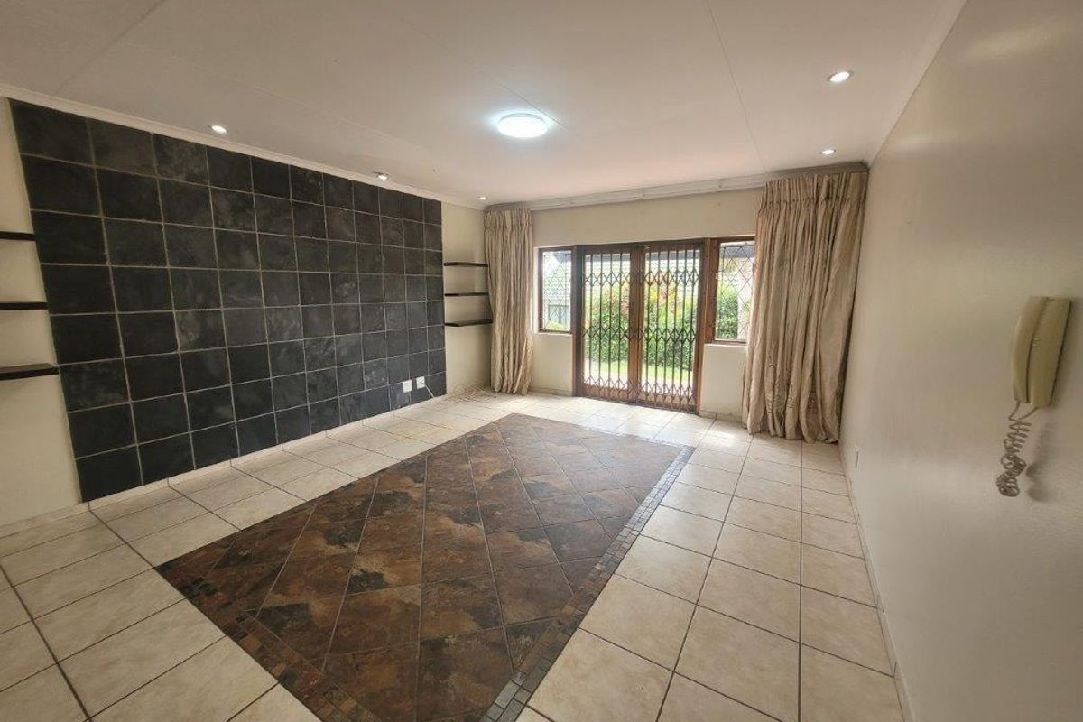 Spacious living area featuring tiled flooring, a dark stone feature wall, and sliding glass doors providing access to the outdoor area.