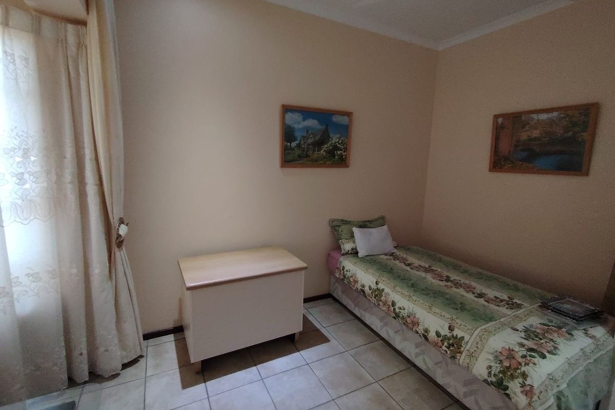 A standard bedroom featuring tiled flooring and neutral wall finishes, providing a functional space with natural light access.