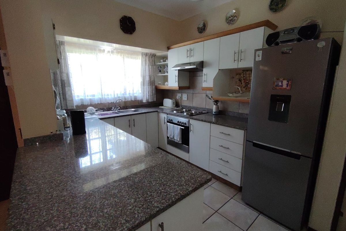 Functional kitchen featuring granite countertops, built-in oven, extractor fan, and ample cabinetry with tiled flooring.