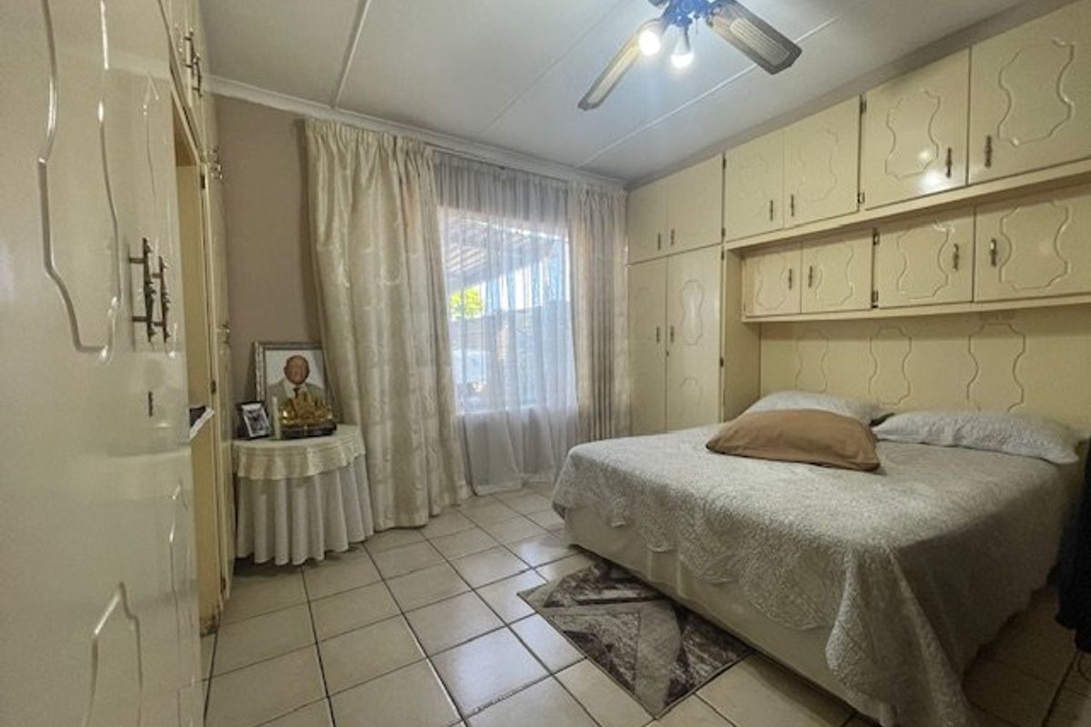 A bedroom featuring tiled flooring, a ceiling fan, and extensive built-in cabinetry providing ample storage space.